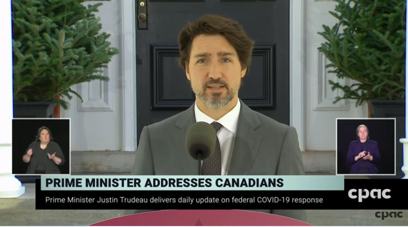 Prime Minister Trudeau addressing Canadians with sign language interpreters in the bottom left and right of the screen.